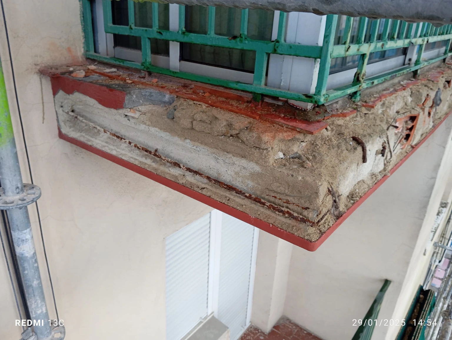 Balcón con zonas de mortero y ladrillo descubiertas durante la reparación