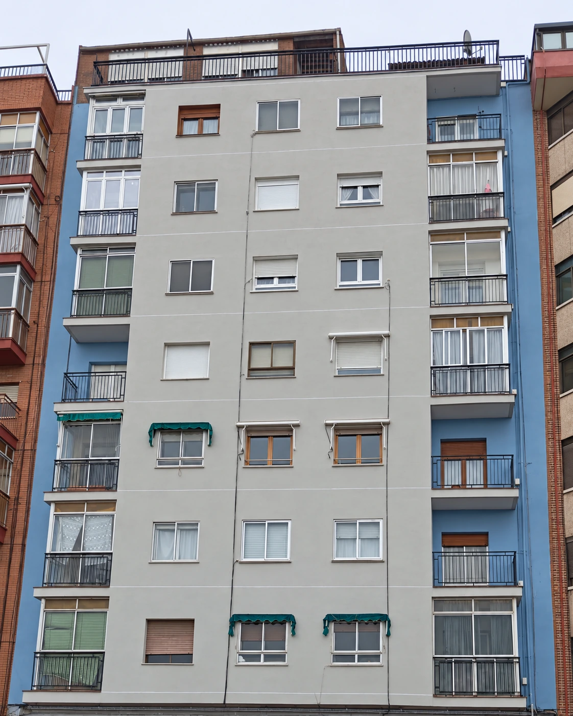 Fachada completa de edificio residencial con balcones y paños azules